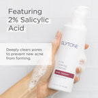 Glytone Acne Clearing Cleanser with 2% Salicylic Acid held by a hand against a light background