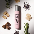 Pink SAMPAR perfume bottle surrounded by dried plants and seeds on a light background